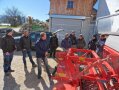 Personen stehen in einem Hof um landwirtschaftliches Gerät