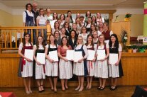 Gruppenbild: Frauen stehen mit Zeugnissen in der Hand hintereinander in einem Saal 